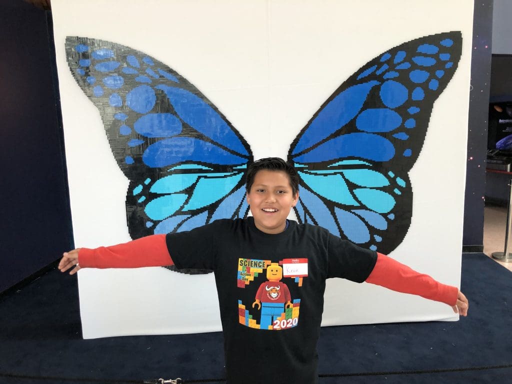 child standing in front of butterfly wings mural