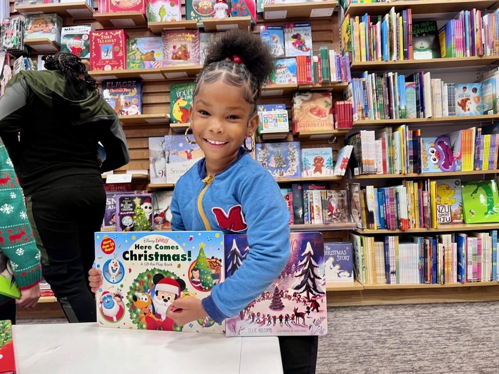 smiling young girl with books at the bookstore