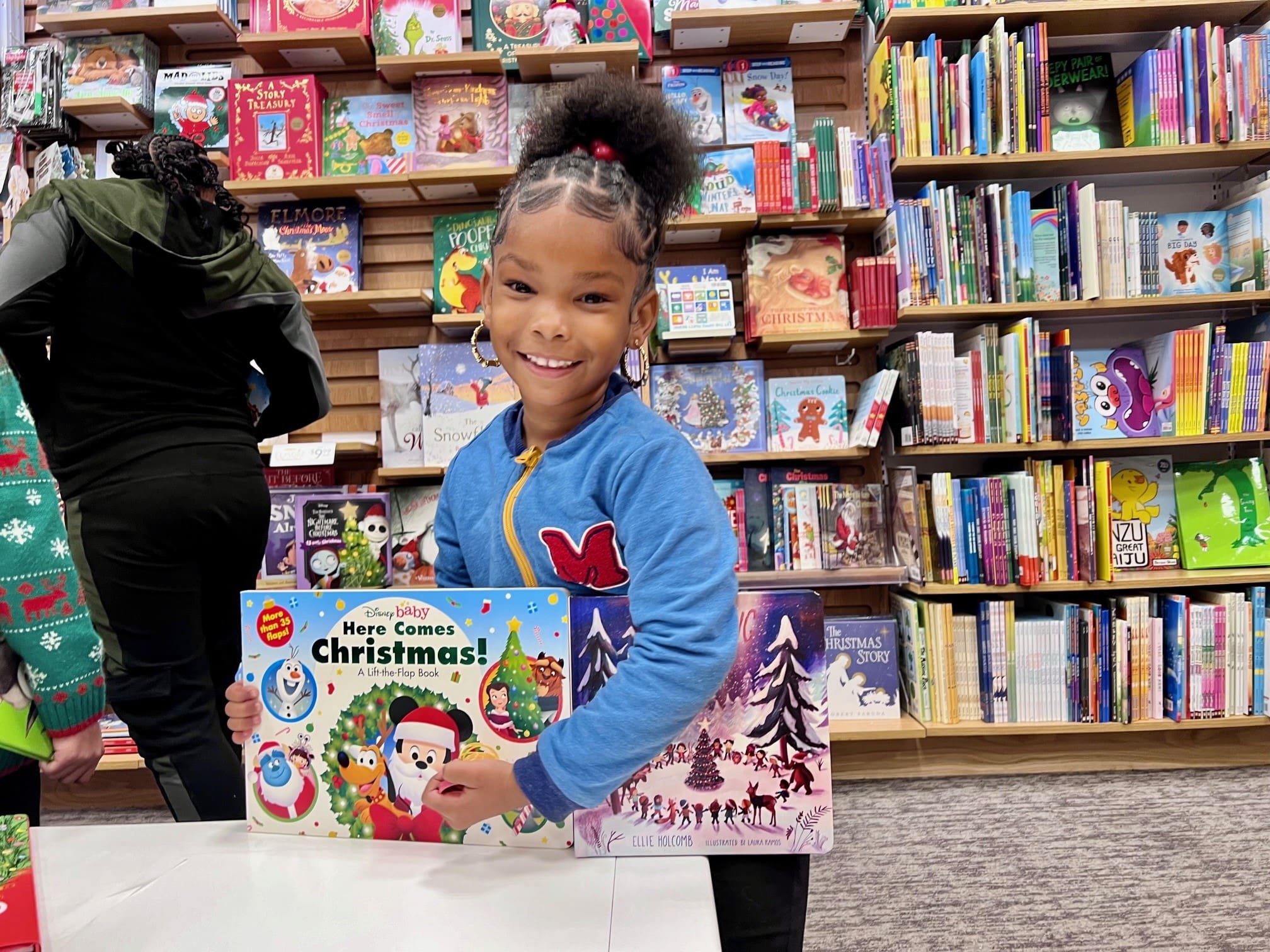 smiling young girl with books at the bookstore we benefit children holiday field trip
