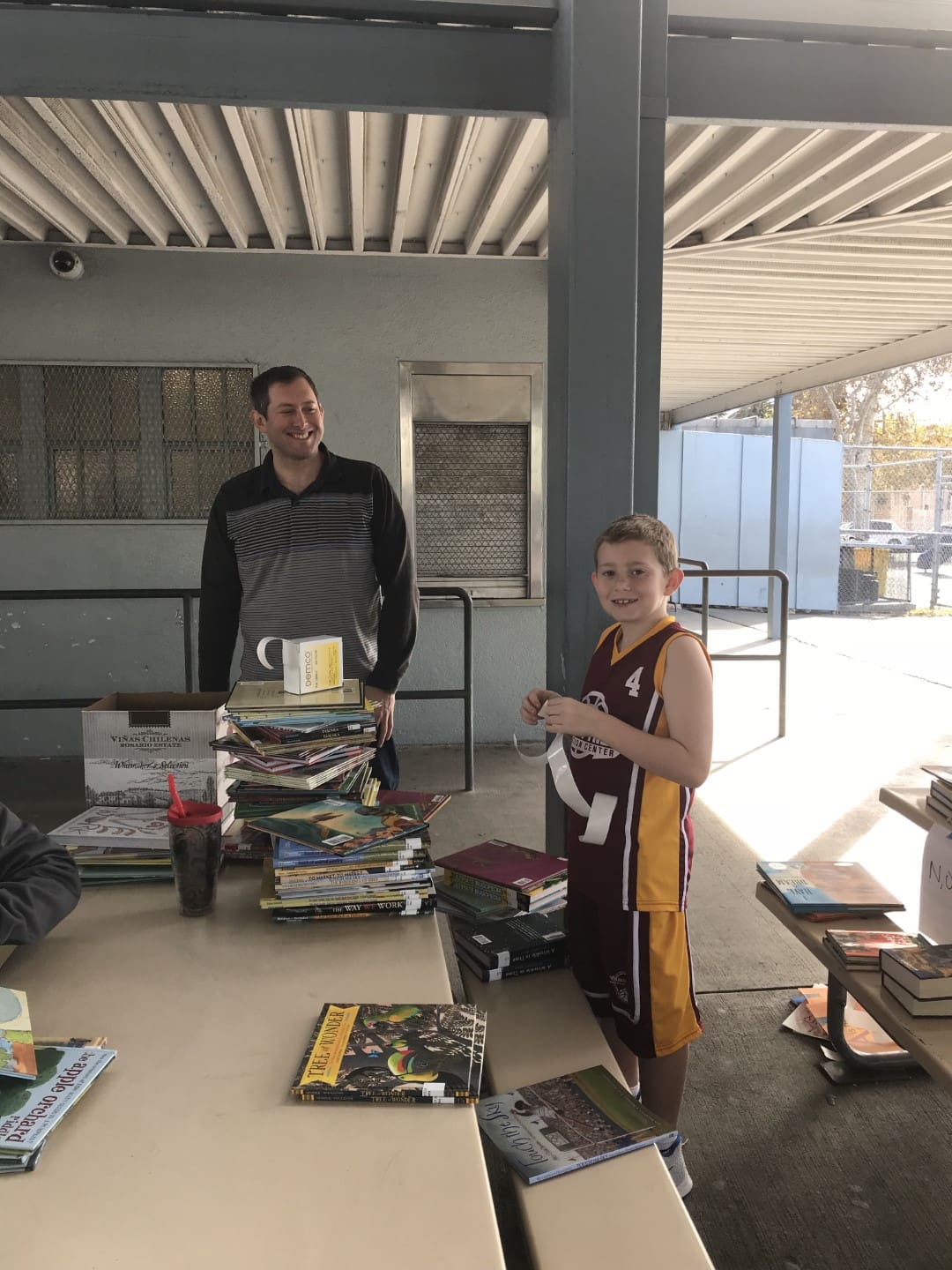 man and boy at a table full of books